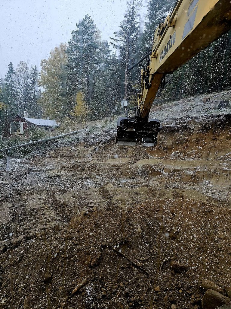 Grävmaskin som arbetar på stenig sluttning i vintermiljö